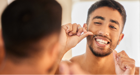 bărbat care utilizează ață dentară